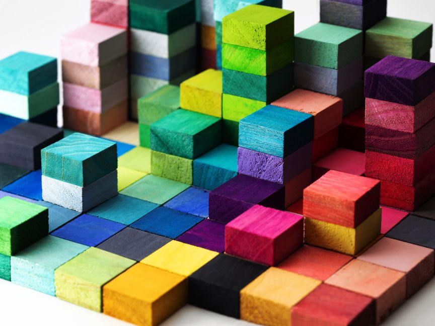 Bunte Holzwürfel in verschiedenen Farben sind zu einem dreidimensionalen Muster in unterschiedlichen Höhen angeordnet.