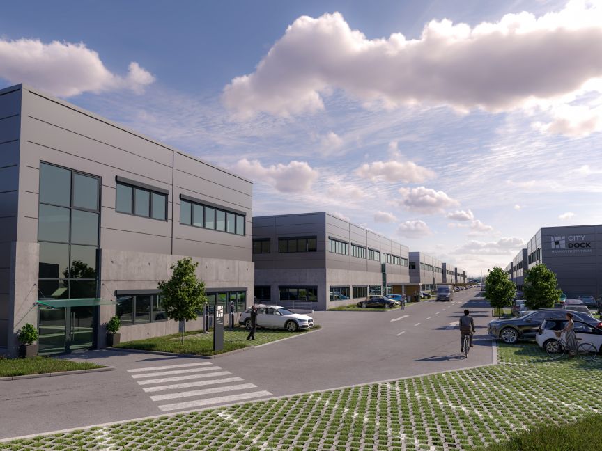 Modernes Gewerbegebiet mit mehrstöckigen Bürogebäuden, Parkplätzen, gepflasterten Wegen und Bäumen unter bewölktem Himmel.