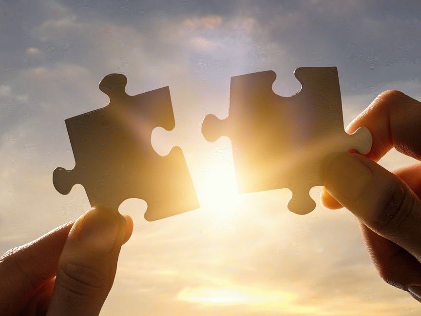 Zwei Hände und zwei Puzzleteile, und in der Mitte der Sonnenschein.