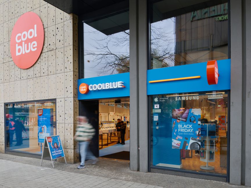 Coolblue-Filiale mit blauer Fassade, Black-Friday-Werbung im Schaufenster, Passanten vor dem Eingang.