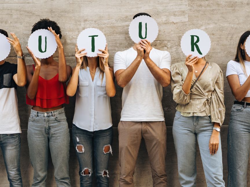 Sechs Personen stehen nebeneinander und halten runde Schilder mit den Buchstaben „FUTURE" vor ihre Gesichter.