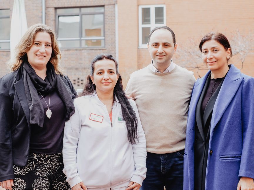 Drei Frauen und ein Mann stehen nebeneinander und gucken in die Kamera.