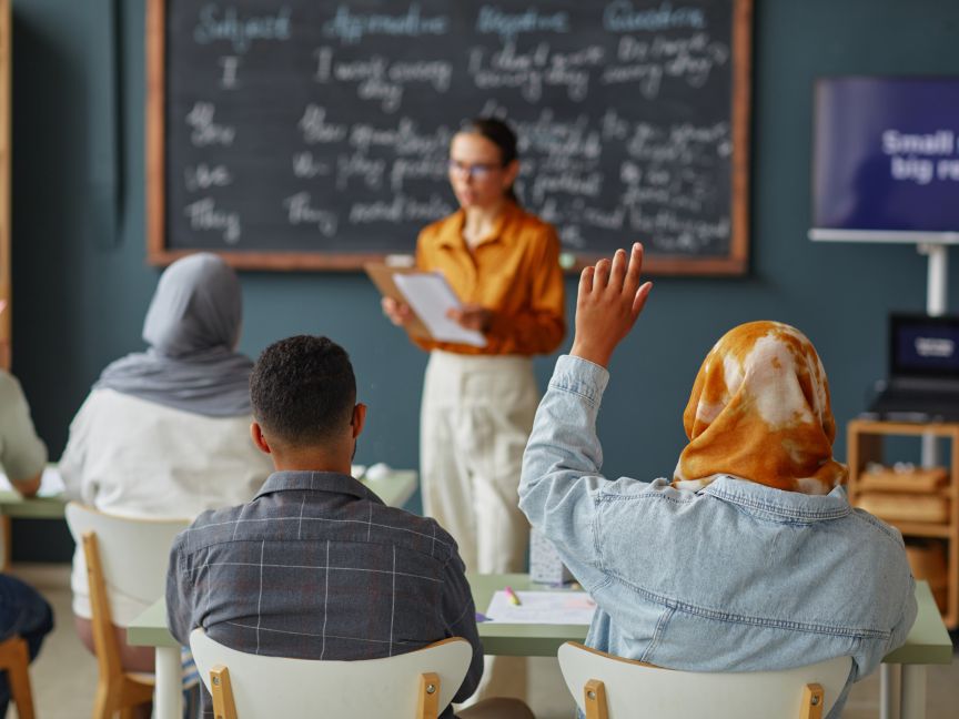 Lehrerin und vier Schüler und Schülerinnen in einem Klassenzimmer.