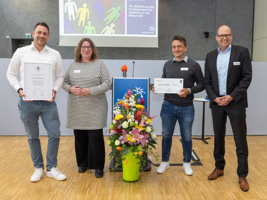 Drei Männer und eine Frau aufgereiht mit zwei Urkunden in der Hand.