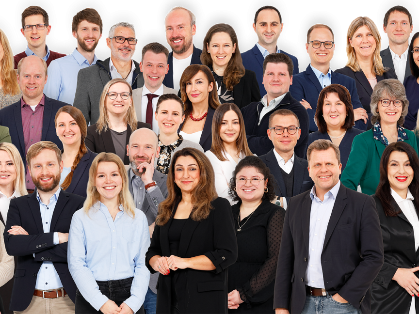 Gruppenfoto von etwa 40 Personen unterschiedlichen Alters und Geschlechts vor weißem Hintergrund, business-casual gekleidet.