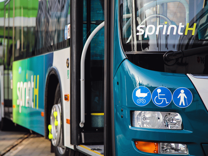 Zwei türkisfarbene Busse der Linie „sprintH" mit Piktogrammen für Kinderwagen, Rollstuhl und Fußgänger.