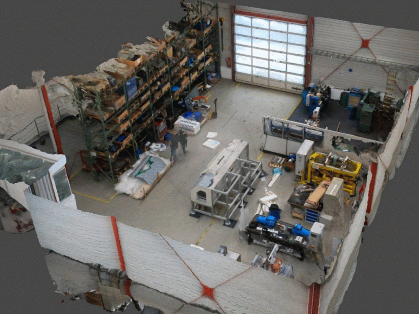 3D-Scan einer Werkstatt mit Regalen, Maschinen, Werkzeugen und einem Rolltor, Vogelperspektive.