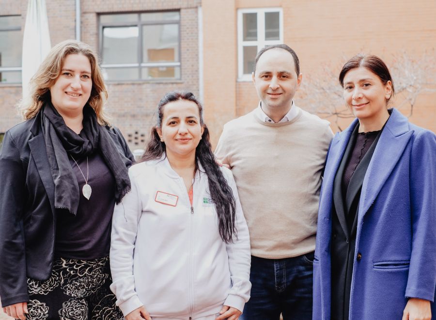 Drei Frauen und ein Mann stehen nebeneinander und gucken in die Kamera.