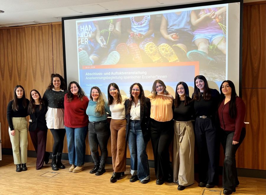 11 Frauen stehen nebeneinander und lächeln.