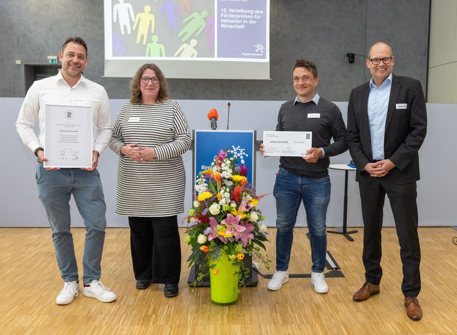 Drei Männer und eine Frau aufgereiht mit zwei Urkunden in der Hand.