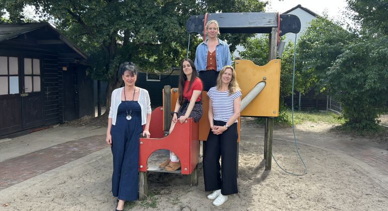 Vier Frauen auf einem Klettergerüst in einem Sandkasten.