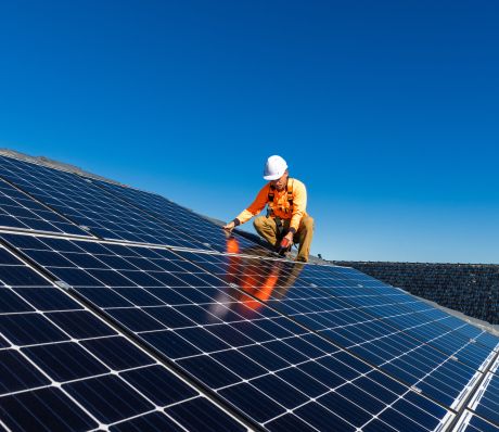 Mann in Arbeitskleidung auf PV-Anlage auf einem Dach.