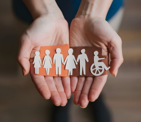 Zwei offene Hände halten Silhouetten von Personen aus Papier.