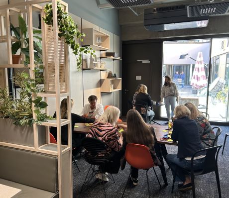 Mehrere Personen in einem Workshop sitzen an mehreren Tischen und arbeiten.