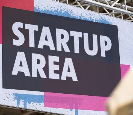 Schild mit der Aufschrift „Startup Area" in weißer Schrift auf dunklem Hintergrund mit blauen und pinken Farbakzenten.