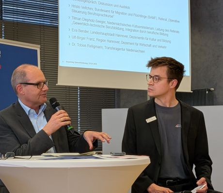 Zwei Männer beim Präsentieren vor einer Leinwand.