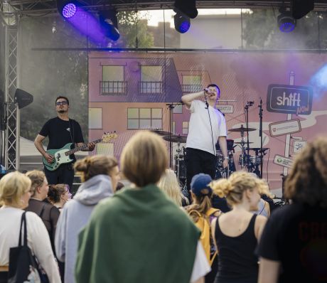 Menschenmenge beim Konzert vor einer Bühne, Sänger auf der Bühne