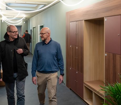Zwei Männer laufen durch einen Büroflur.