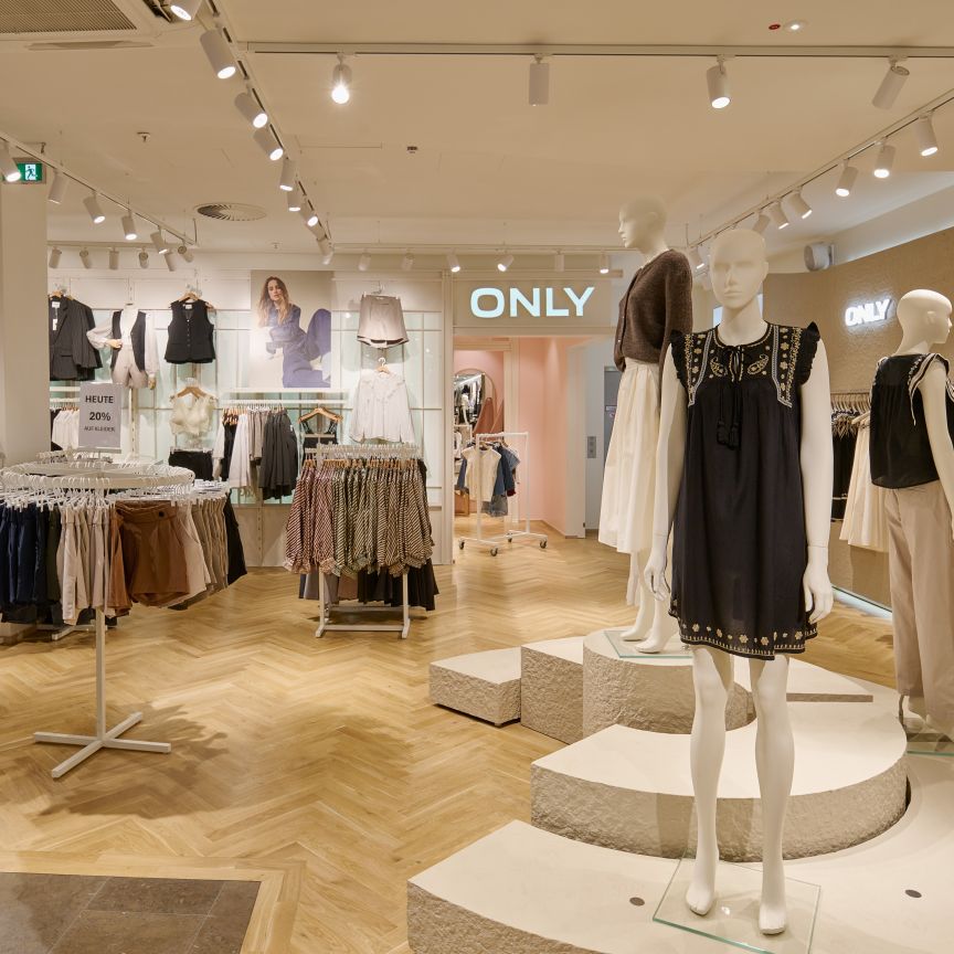Modeboutique „Only" mit zwei Schaufensterpuppen, Kleiderständern und hellem Holzboden unter Strahlerbeleuchtung.