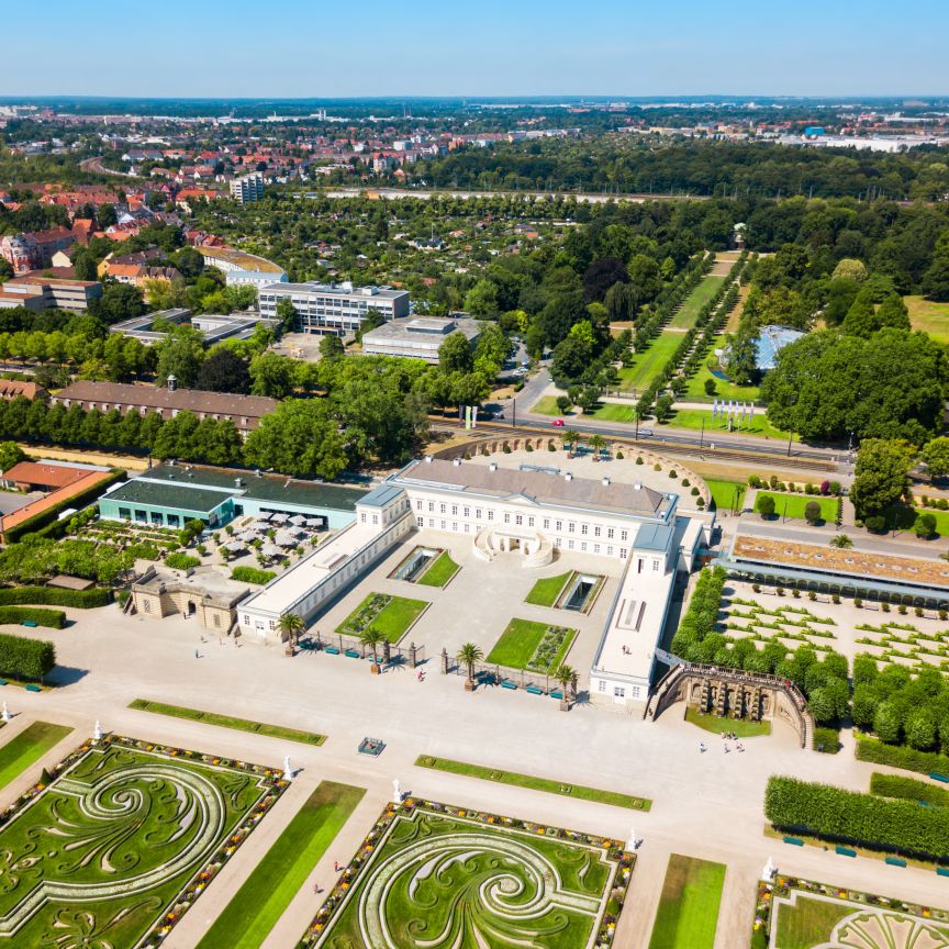 Luftaufnahme eines barocken Schlosses mit geometrisch angelegten Gartenanlagen, umgeben von Stadtbebauung und Bäumen.