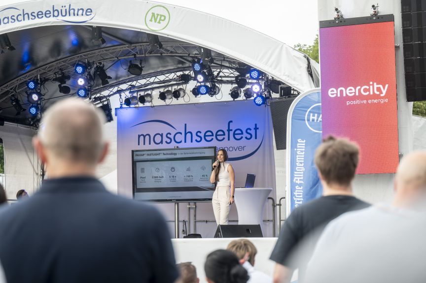 Frau spricht auf der Bühne des Maschseefests Hannover, Sponsoren-Banner von enercity und NP im Hintergrund.
