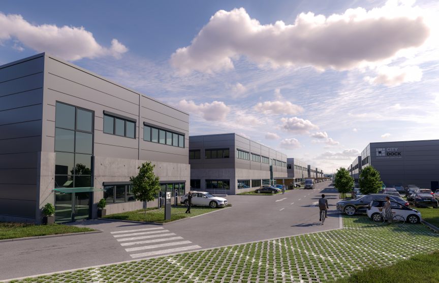 Modernes Gewerbegebiet mit mehrstöckigen Bürogebäuden, Parkplätzen, gepflasterten Wegen und Bäumen unter bewölktem Himmel.