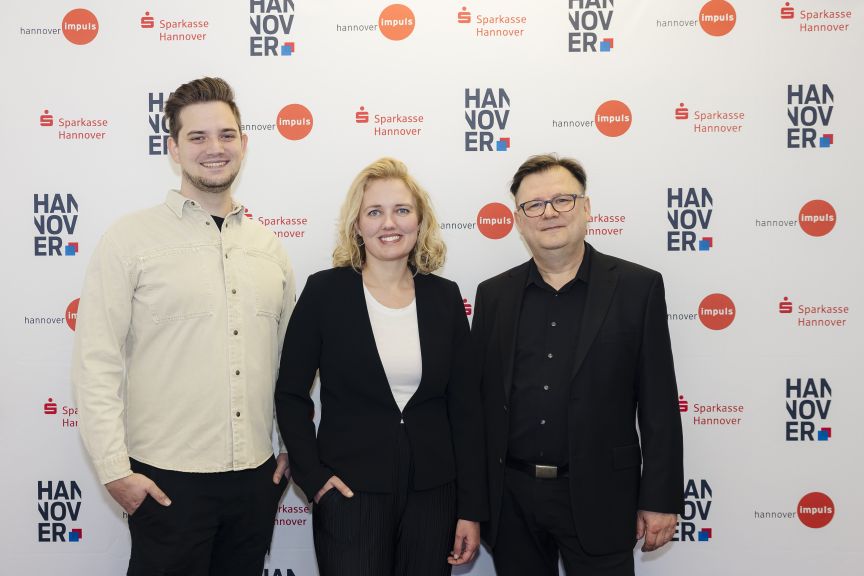 Drei Personen stehen vor einer Pressewall mit Logos von Sparkasse Hannover und hannover impuls.