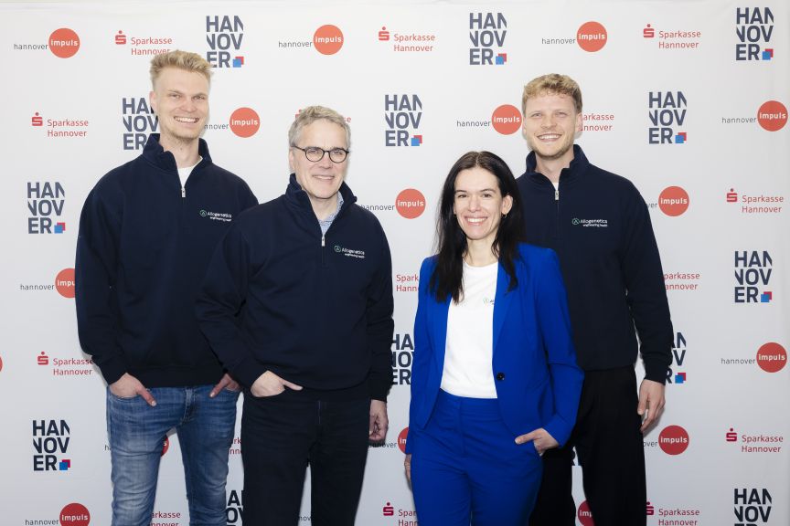 Vier Personen posieren lächelnd vor einer Hannover-Impuls- und Sparkasse-Hannover-Logowall.