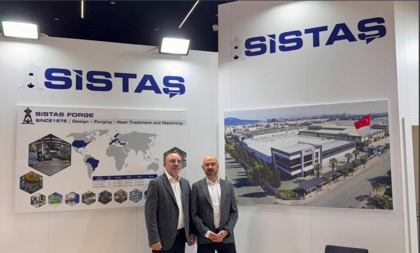 Zwei Männer stehen vor einem Messestand der Firma Sistas Forge mit Weltkartenplakat und Fabrikfoto.