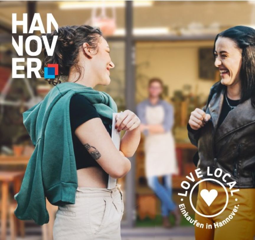 Zwei Frauen lachen sich an vor einem Geschäft. Logo „Hannover" und „Love Local – Einkaufen in Hannover".