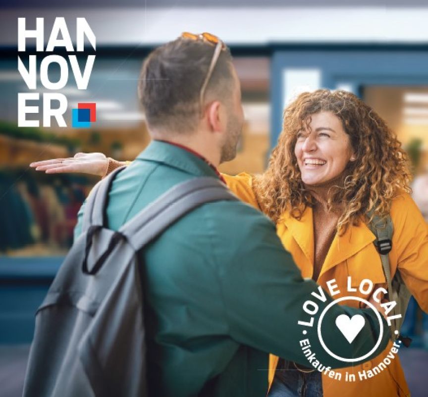 Zwei Personen begrüßen sich lächelnd. Logo „Hannover" und „Love Local – Einkaufen in Hannover" sichtbar.
