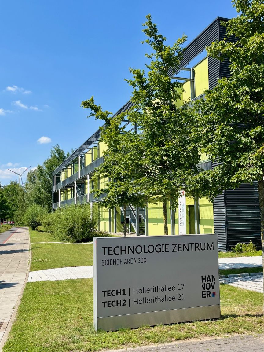 Schild „Technologie Zentrum Hannover, Science Area 30X" vor modernem Gebäude mit gelben Fassadenelementen und Bäumen.
