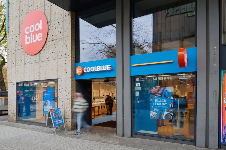 Coolblue-Filiale mit blauer Fassade, Black-Friday-Werbung im Schaufenster, Passanten vor dem Eingang.