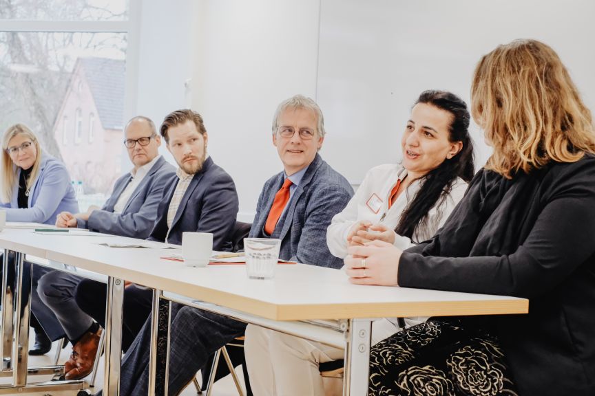 Sechs Personen sitzen an einem Tisch, 3 Männer und 3 Frauen.