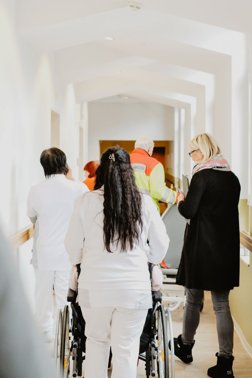 Vier Personen der Diakonie auf der Arbeit laufen in einem Flur weg von der Kamera.