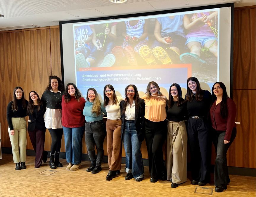 11 Frauen stehen nebeneinander und lächeln.