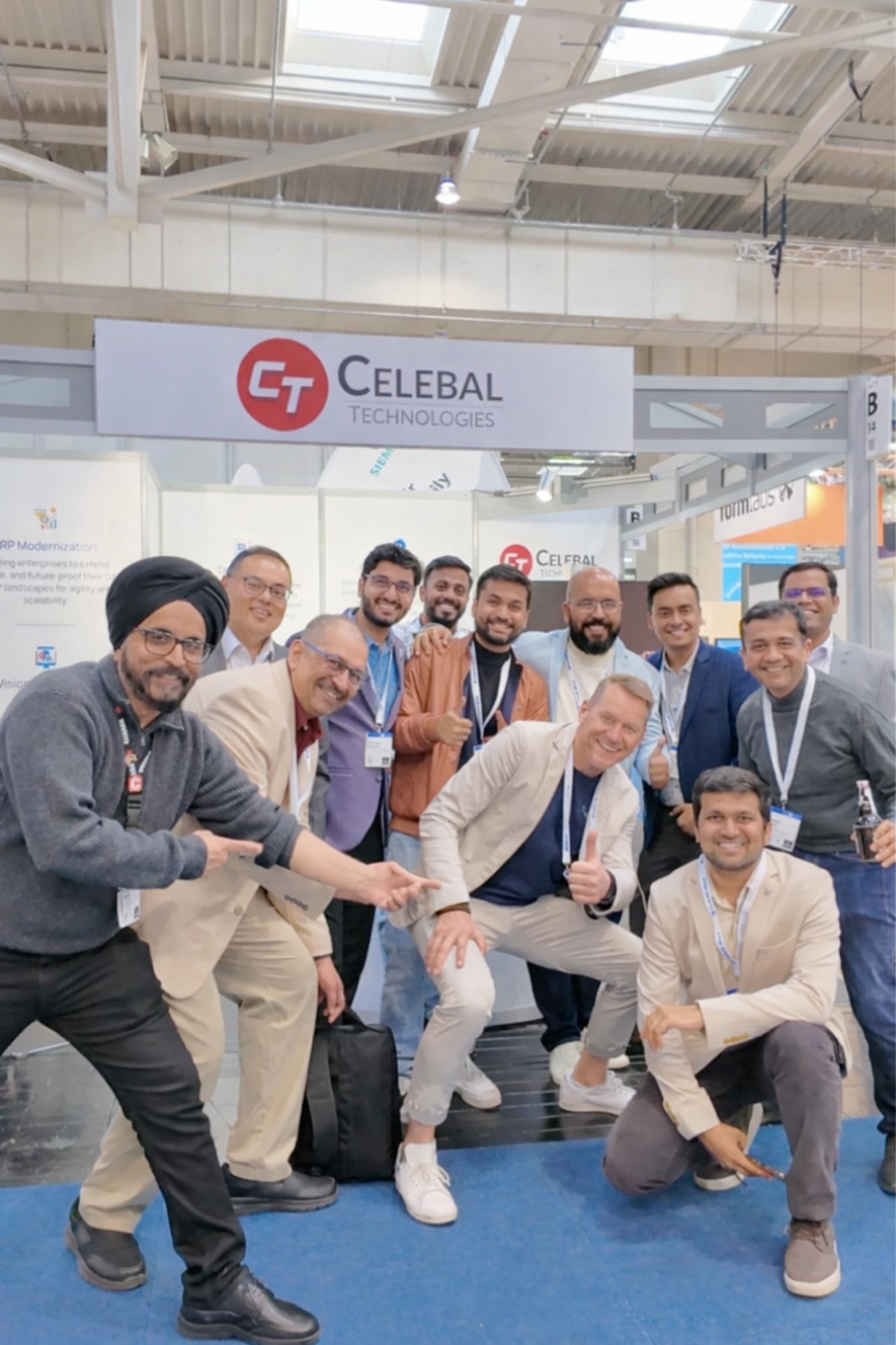 Gruppe von Männern posiert lächelnd vor dem Messestand von Celebal Technologies in einer Ausstellungshalle.