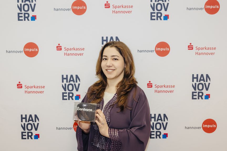 Frau hält Produkt mit Aufschrift „Banbona" vor Hannover-Impuls- und Sparkasse-Hannover-Hintergrund.