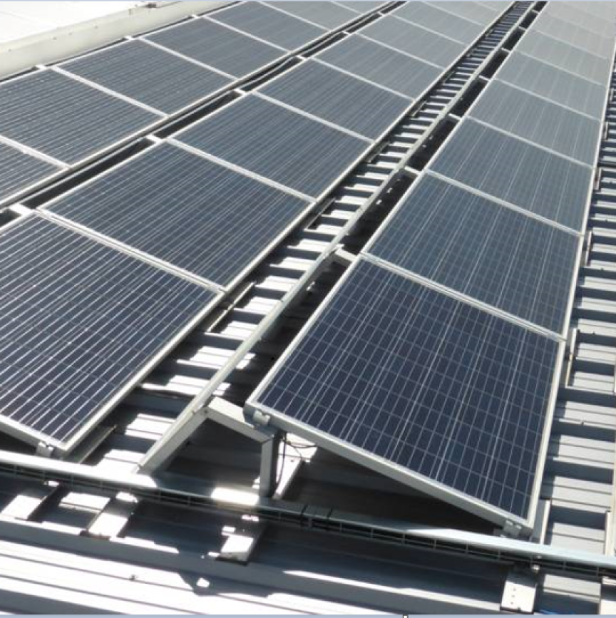 Mehrere Solarpanele auf einem Flachdach, montiert auf metallischen Halterungsgestellen, in Reihen angeordnet.