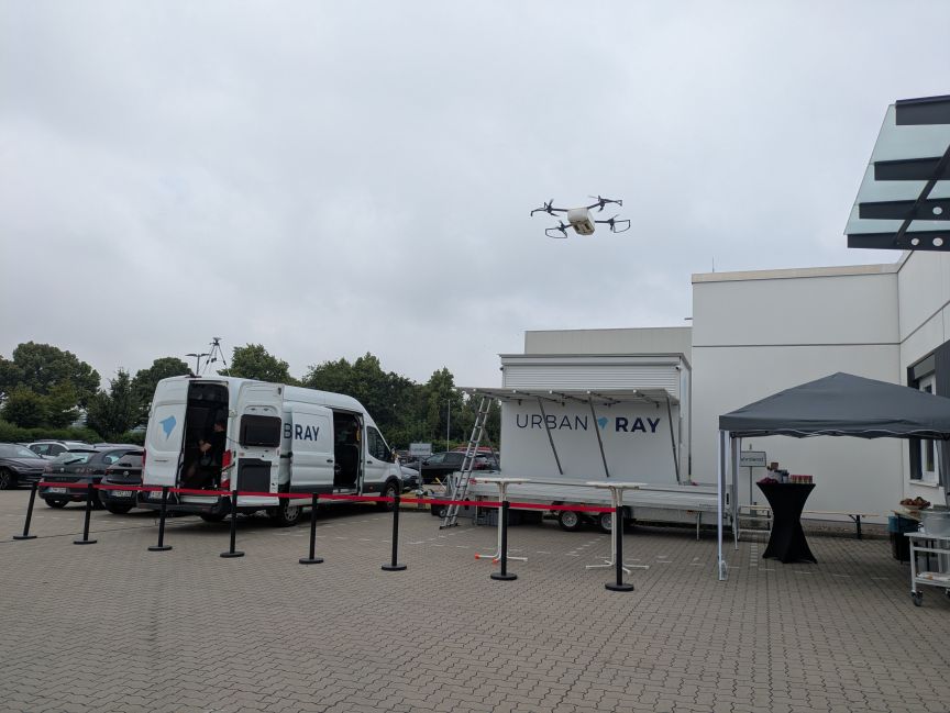 Drohne in der Luft, im Hintergrund Transporter und Container von Urban Ray.
