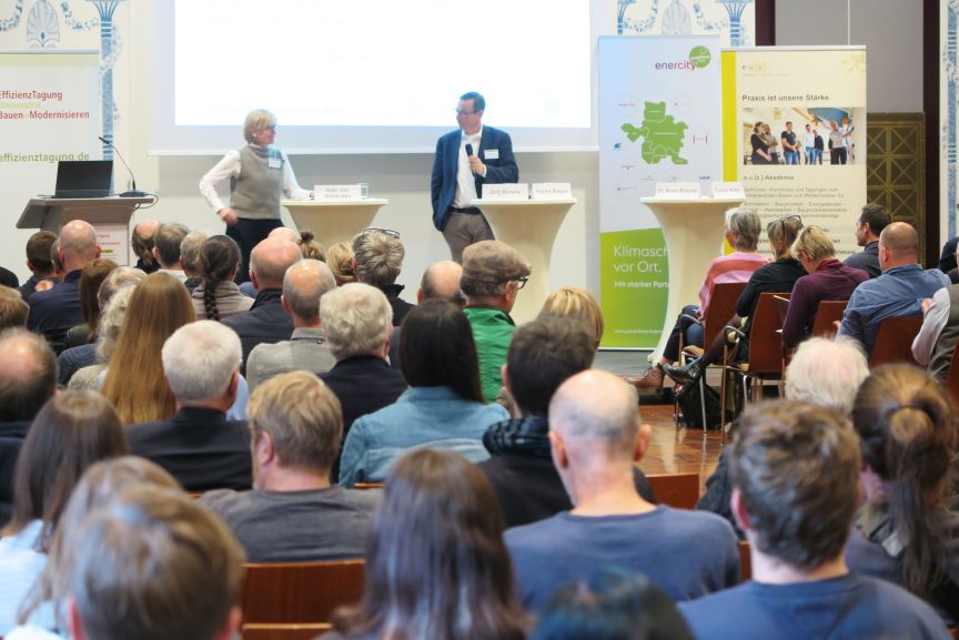 Plenum mit Publikum und zwei Personen auf der Bühne.
