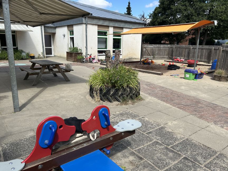Innenhof vom Kindergarten mit Wippe und Sandkasten.