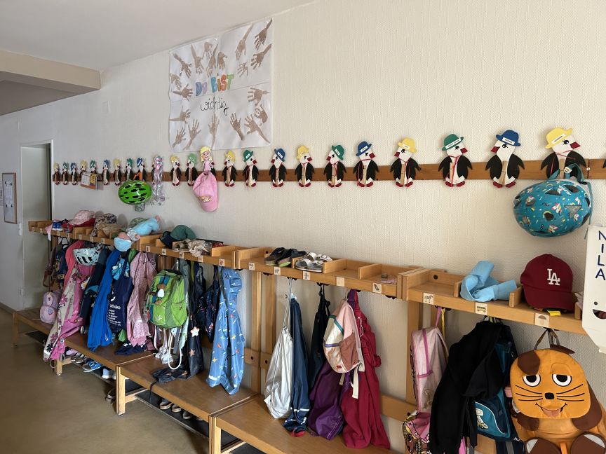 Umkleidebank im Kindergarten mit Kinderjacken und Kinderrucksäcken.