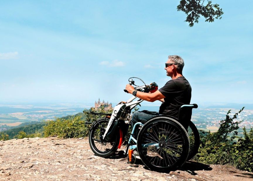 Mann mit Sportrollstuhl auf Berggipfel