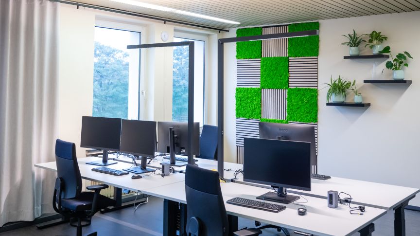 Schreibtische mit Stühlen im Büro und Mooswand