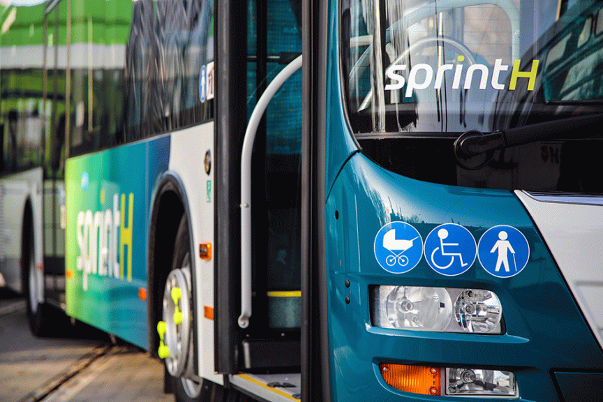 Zwei türkisfarbene Busse der Linie „sprintH" mit Piktogrammen für Kinderwagen, Rollstuhl und Fußgänger.