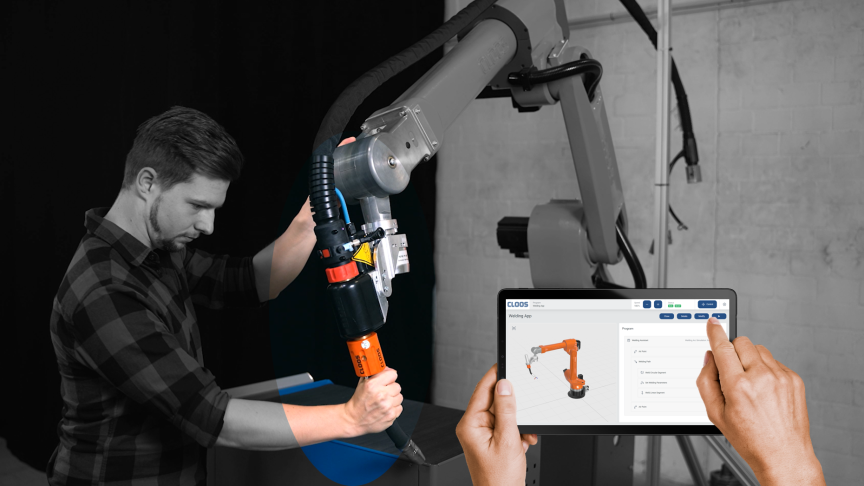 Mann in kariertem Hemd bedient Roboterarm; Hände halten Tablet mit 3D-Robotermodell auf dem Bildschirm.